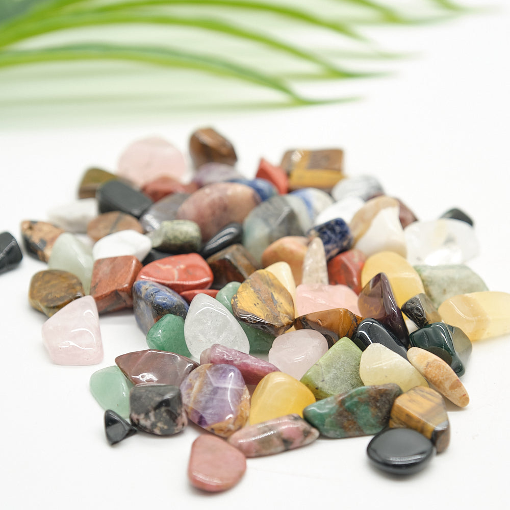 Assorted colorful stones on a white background with green leaves.