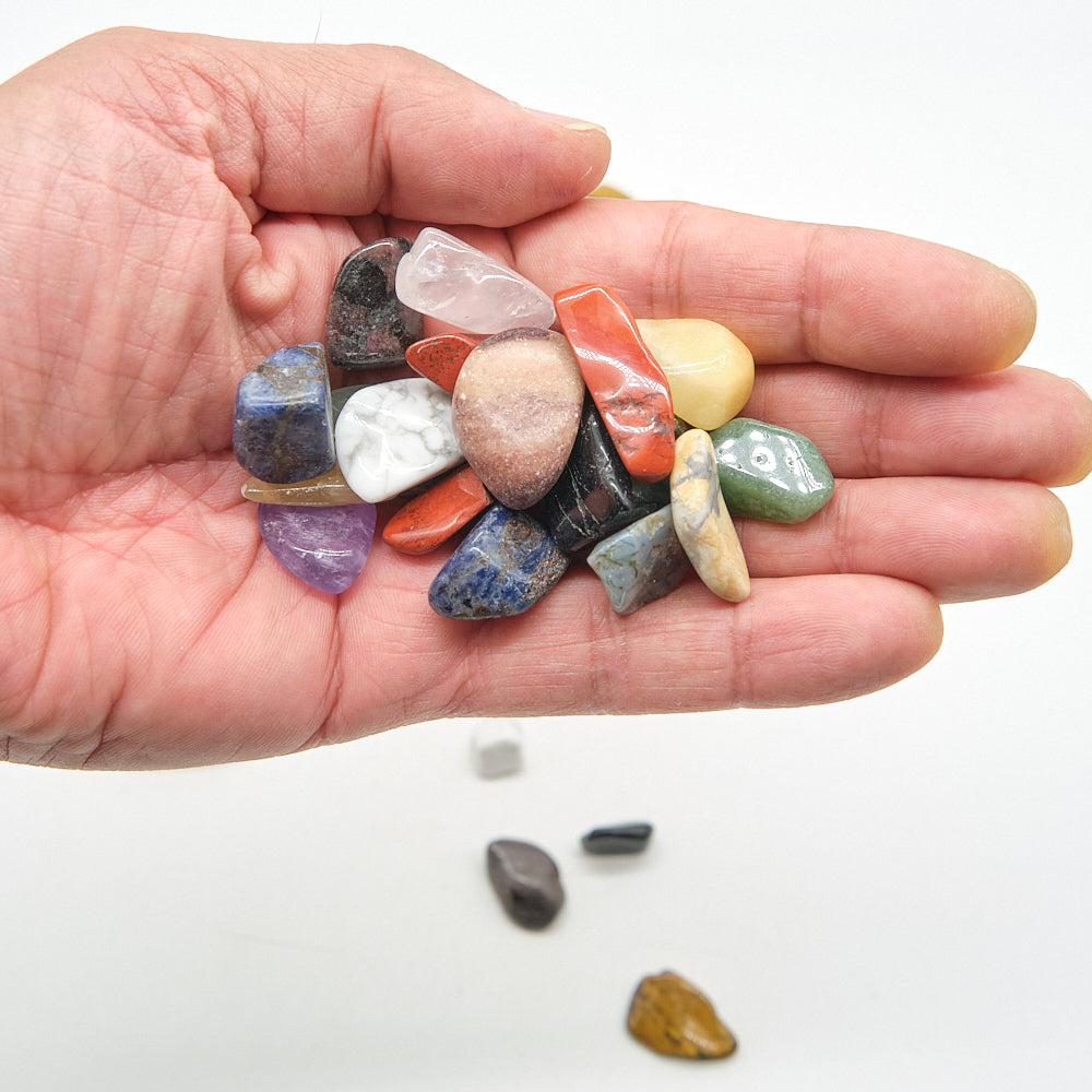 Hand holding a collection of multicolored stones on a white background