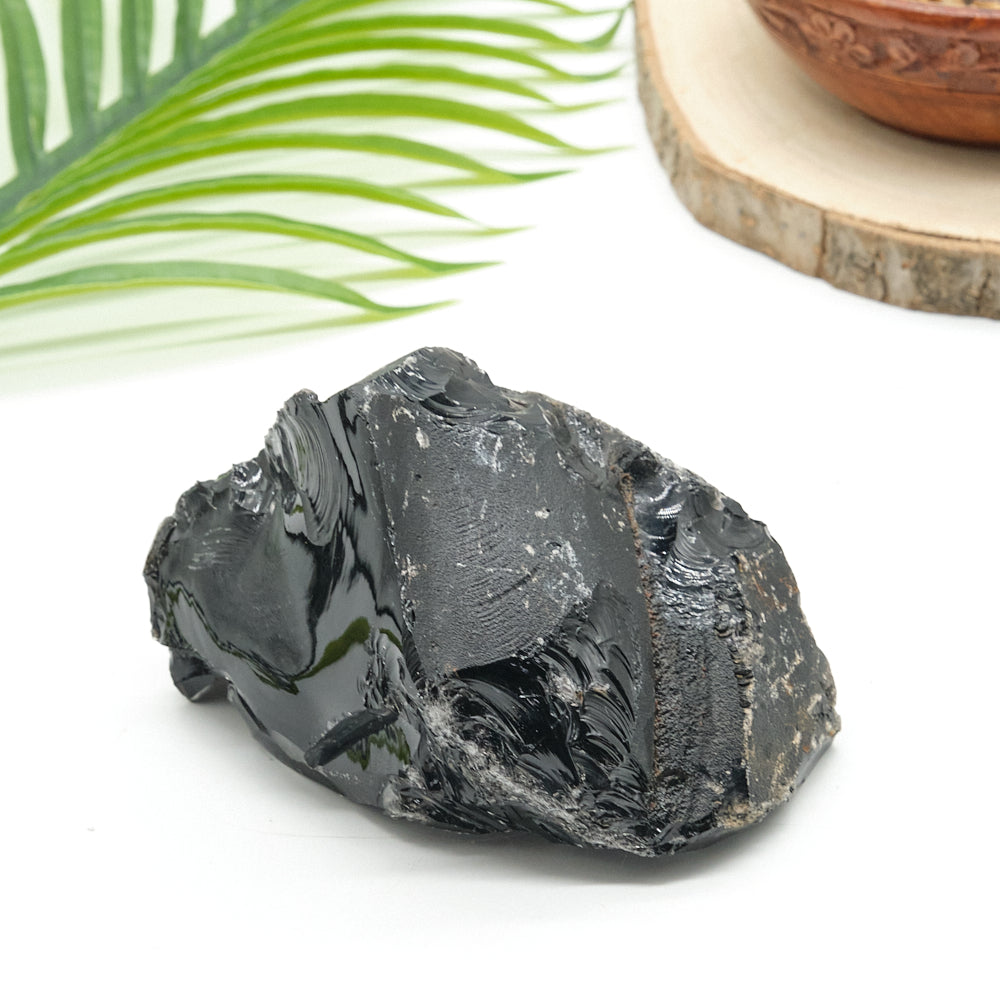 raw Black stone on a white surface with green leaves in the background