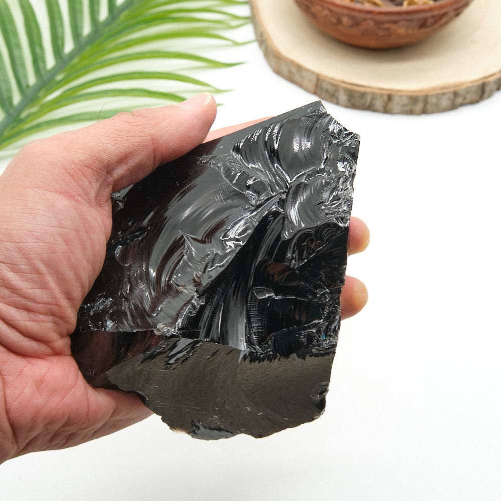 Hand holding a large piece of obsidian with a blurred background