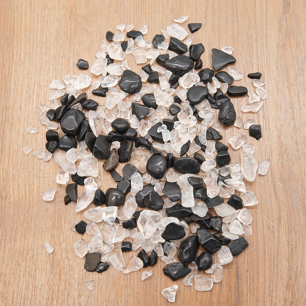 Black tourmaline and clear quartz chips on a wooden surface