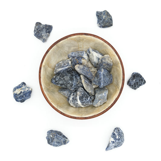 Bowl filled with blue sodalite stones on a white background
