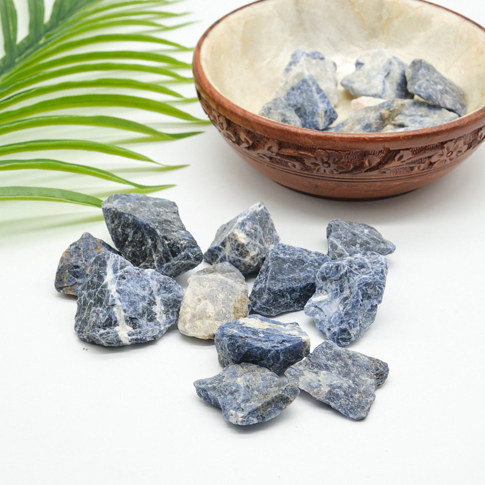 Bowl filled with blue sodalite stones on a white background
