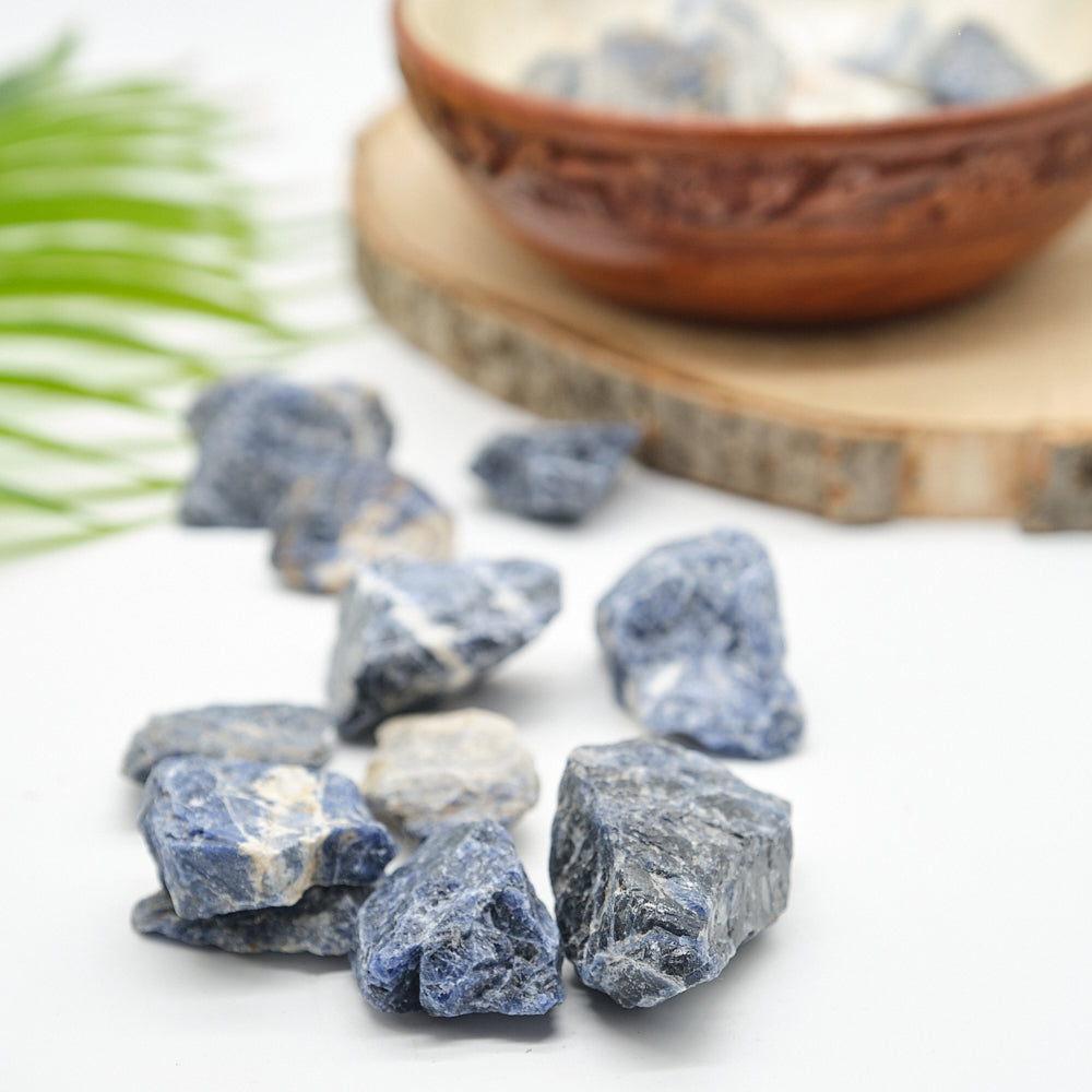 Bowl filled with blue sodalite stones on a white background