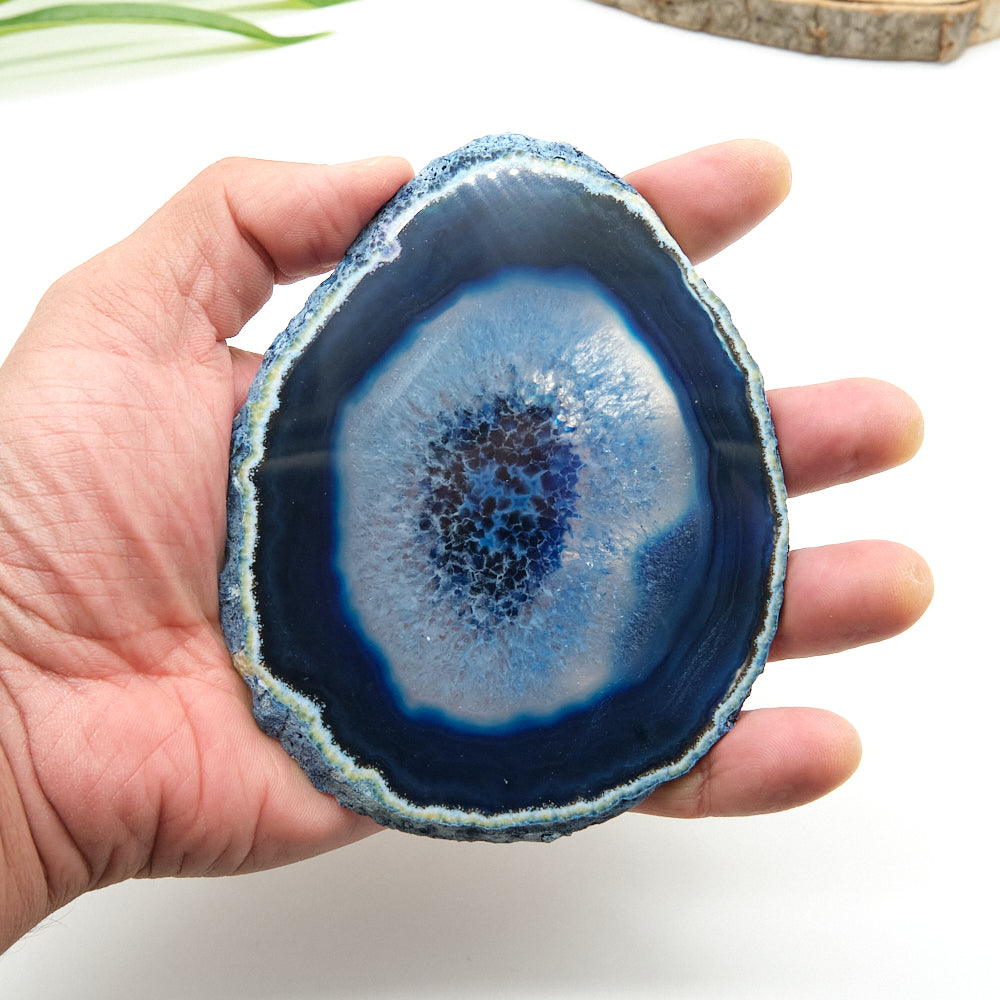 Hand holding a blue agate stone with concentric layers