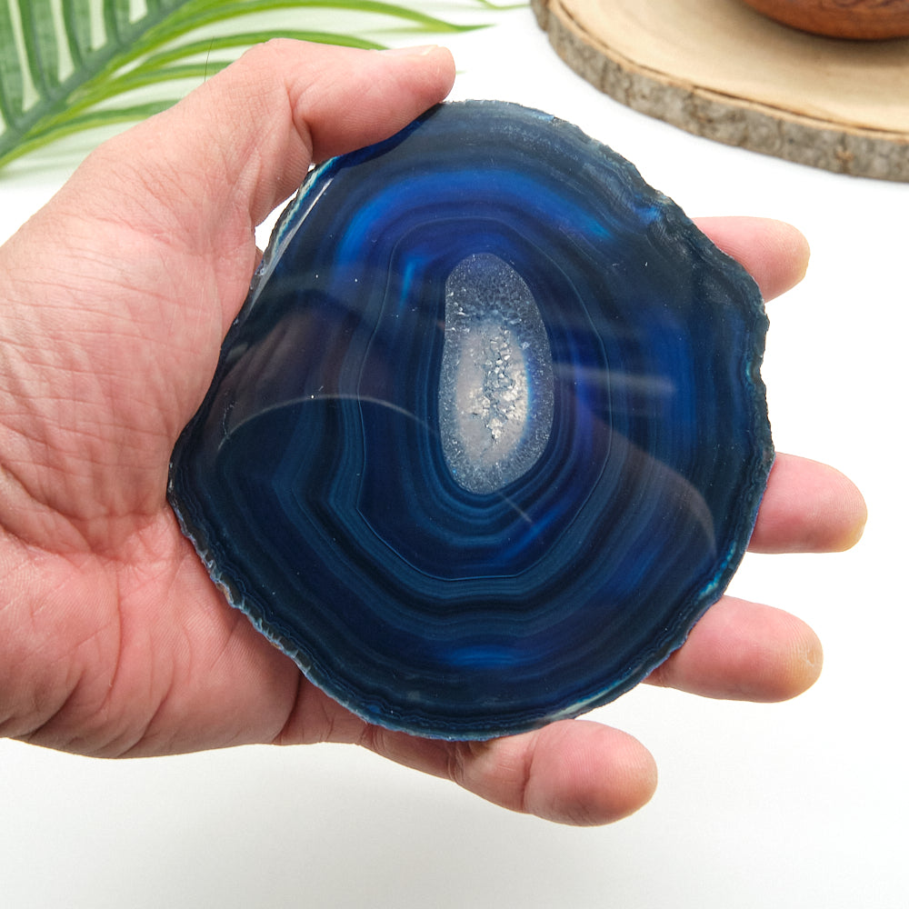 Hand holding a blue agate stone with a white background