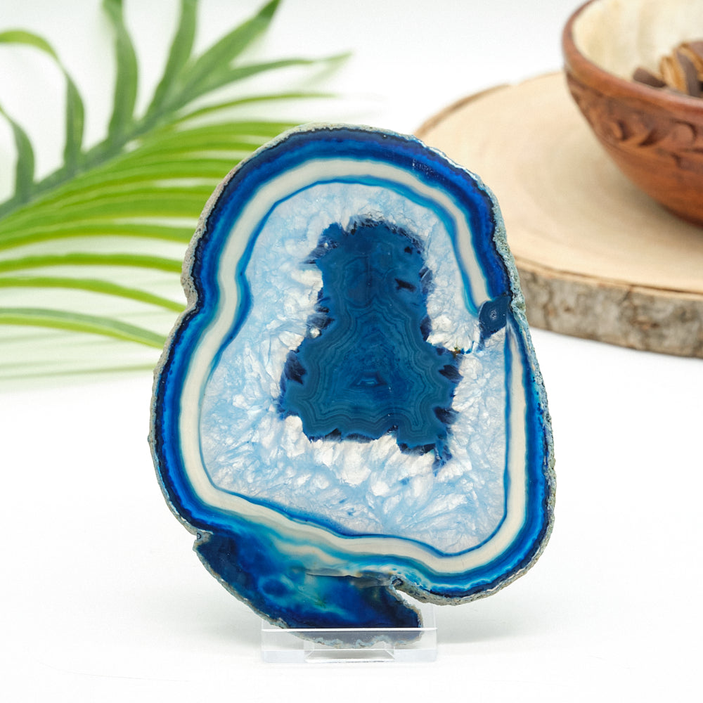 Blue and white agate crystal on a white background with a leaf and wooden bowl in the background