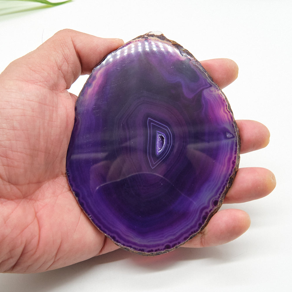 Hand holding a purple agate stone against a white background