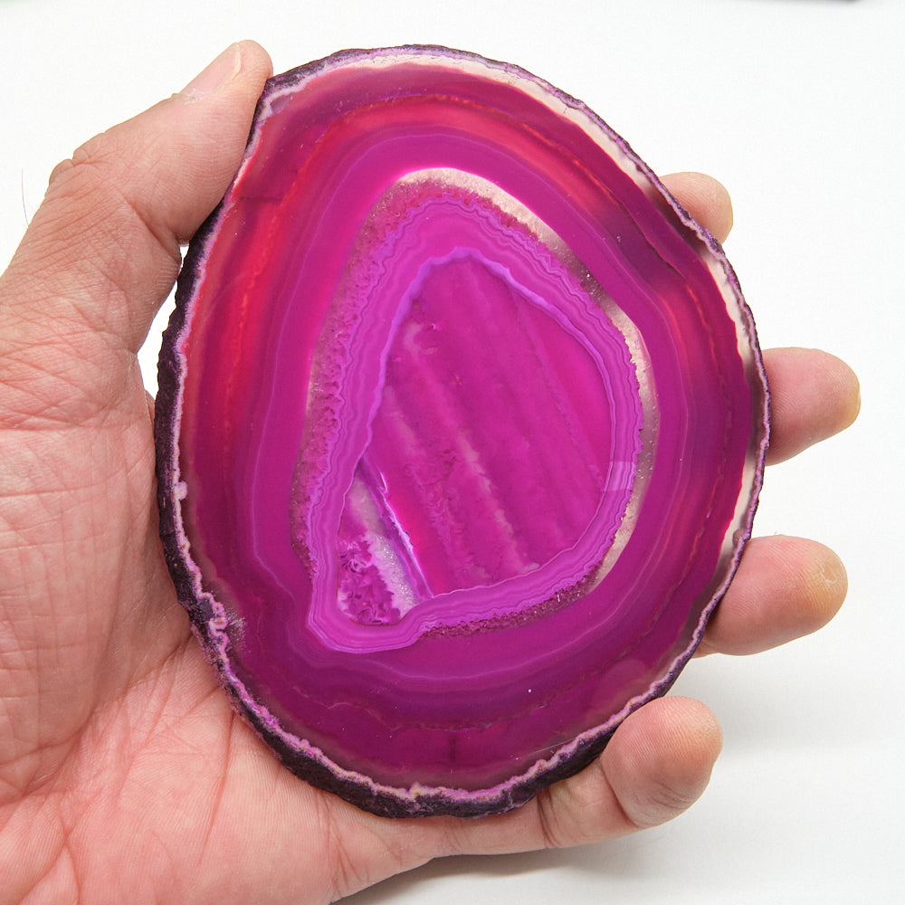 Hand holding a vibrant pink agate stone against a white background