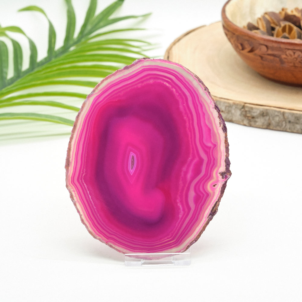 Pink agate stone with a bowl of dried herbs and green leaves in the background