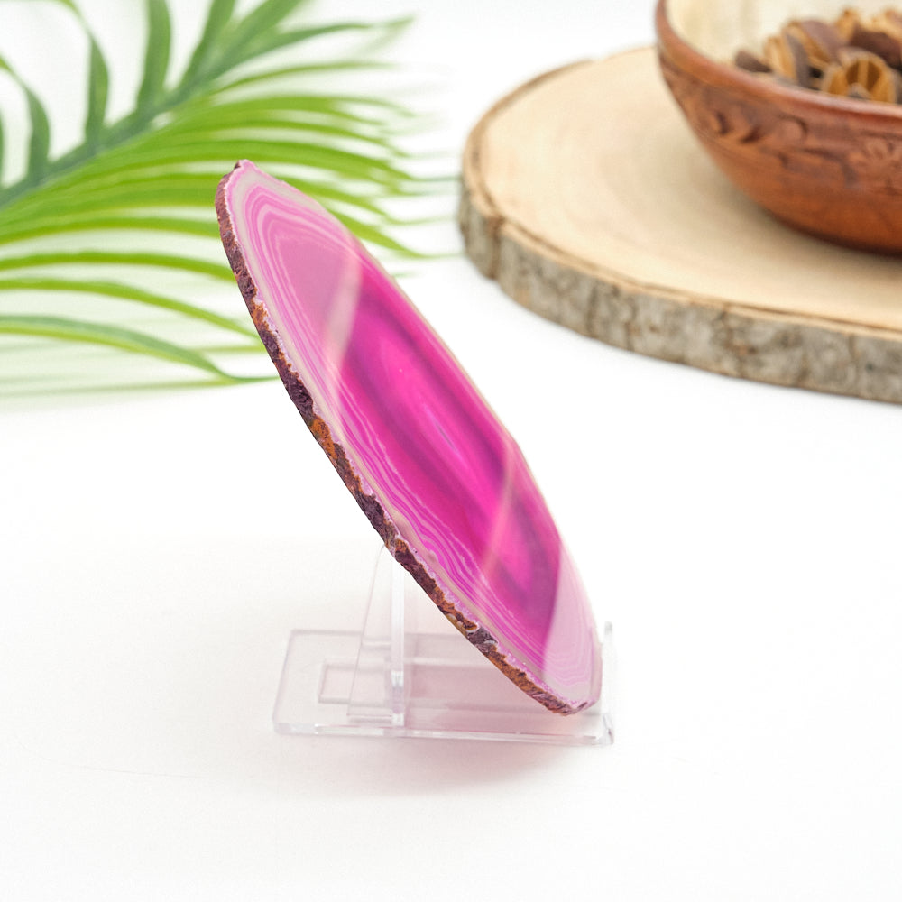 Pink agate slice on a clear stand with a natural background