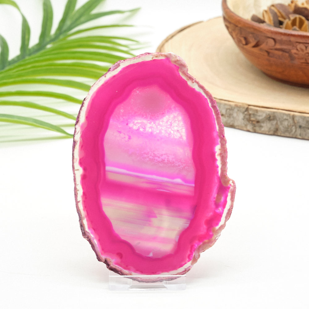 Pink agate stone on a white surface with a green leaf in the background