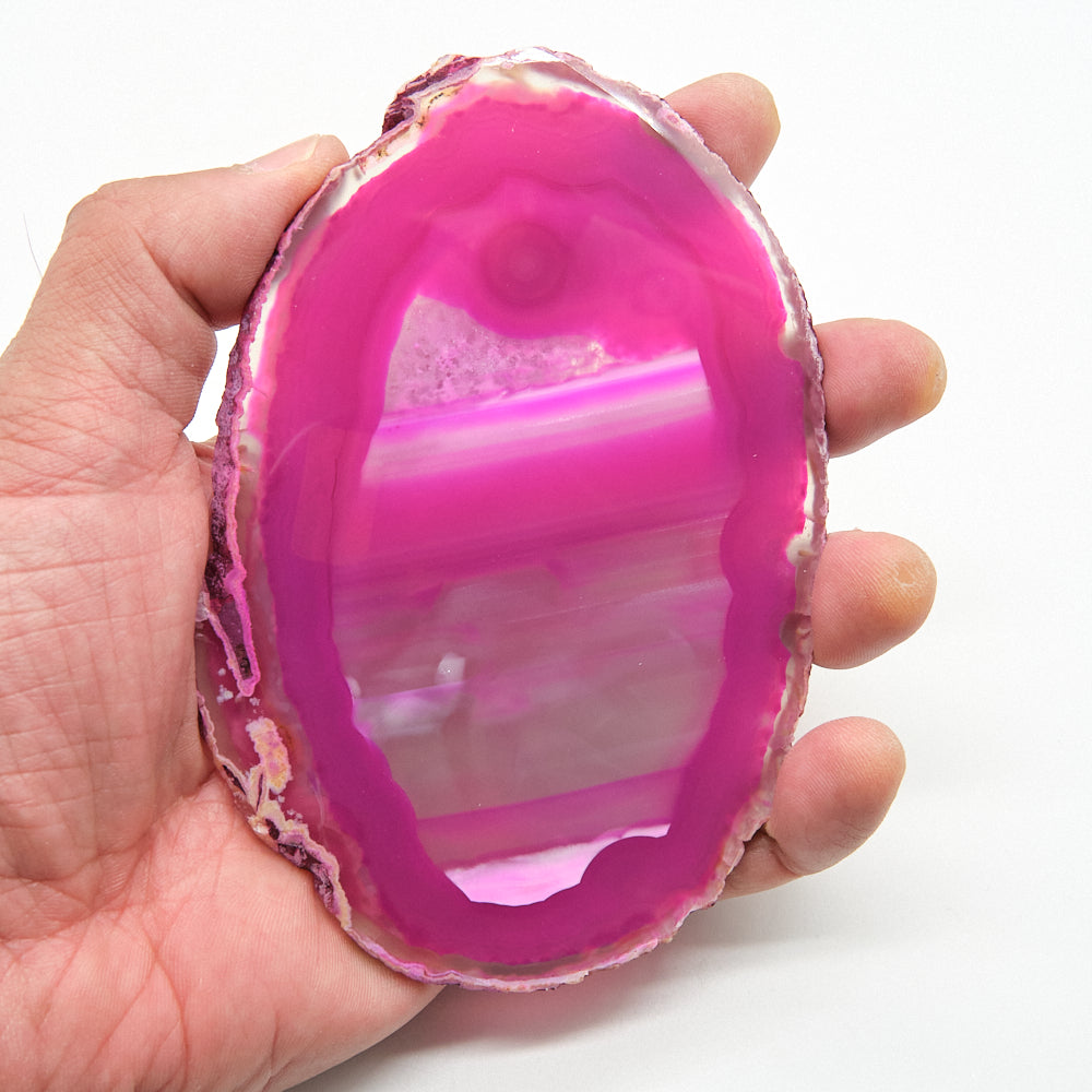 Hand holding a pink and white agate stone against a white background