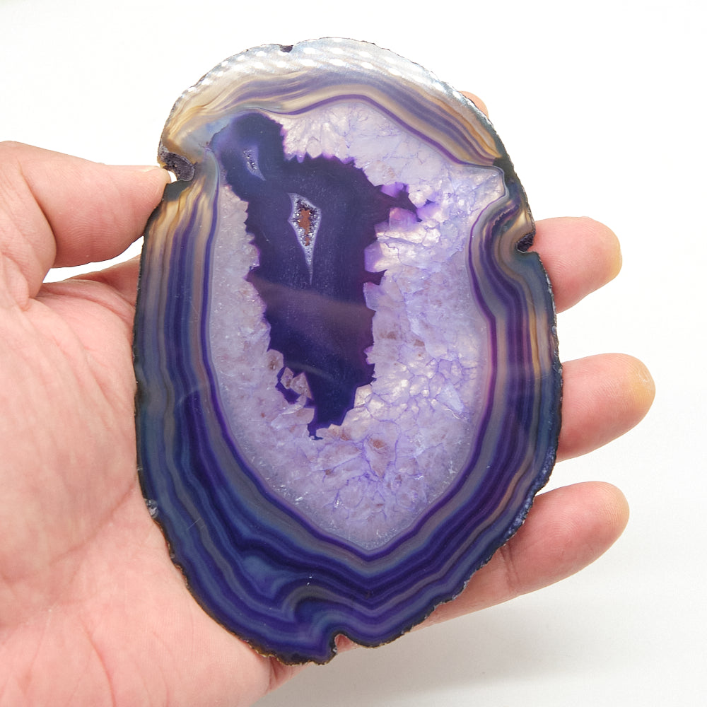 Hand holding a purple and white agate stone against a white background