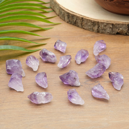 Amethyst crystals on a wooden surface with green leaves in the background