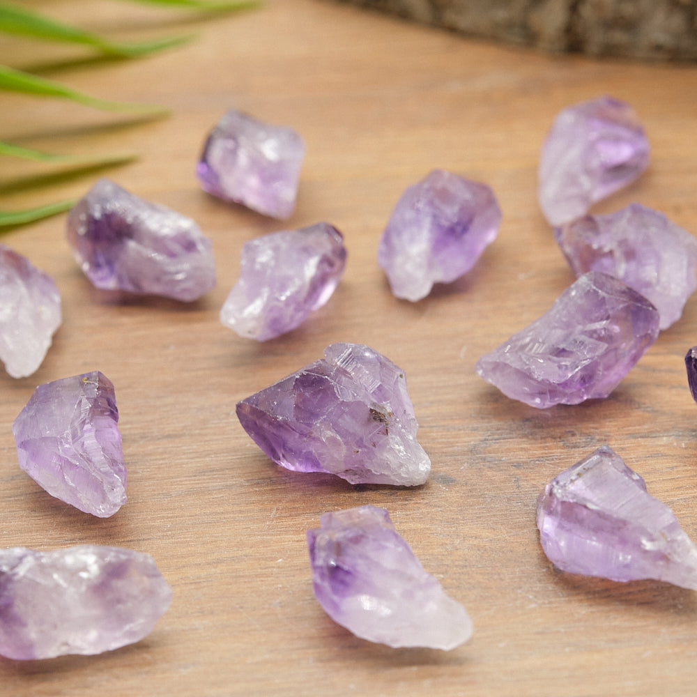 Purple amethyst crystal points rocks on a wooden surface with grass in the background