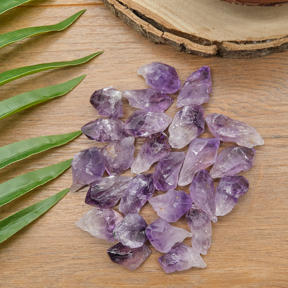 Amethyst crystals on a wooden surface with green leaves