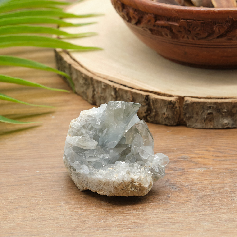 celestite Crystal on a wooden surface with a terracotta pot in the background