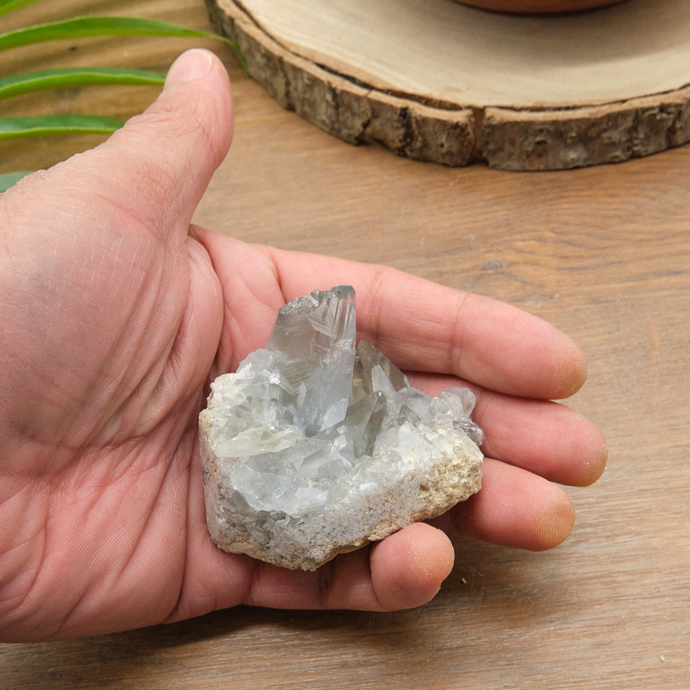 Hand holding a crystal rock on a wooden surface