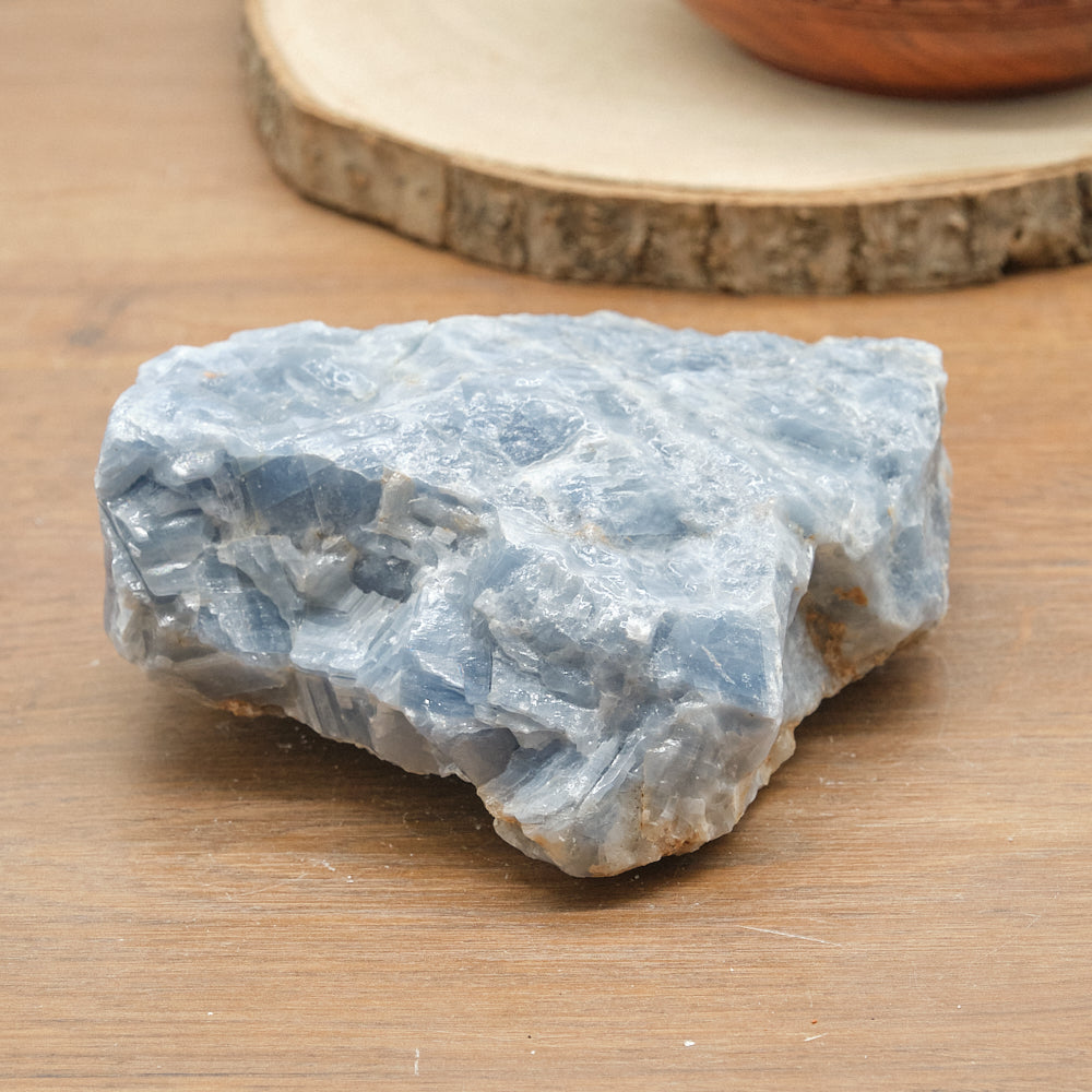 Raw blue calcite crystal on a wooden surface