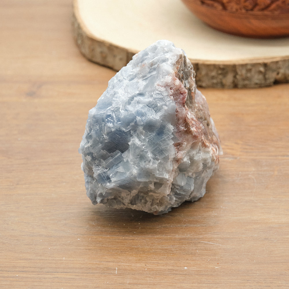 Raw calcite crystal rock on a wooden surface with a blurred background