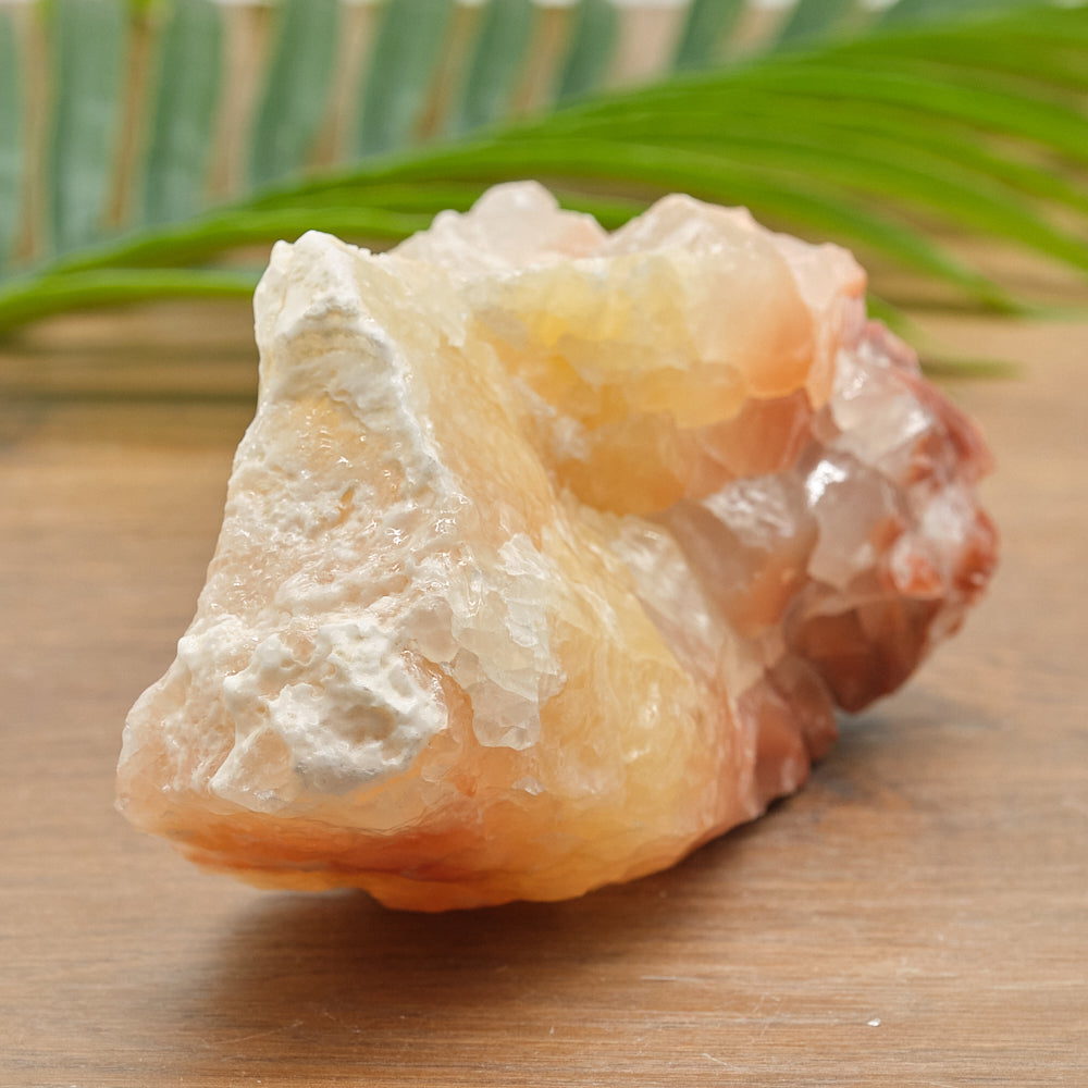 yellow red calcite rock on a wooden surface with a green leaf in the background