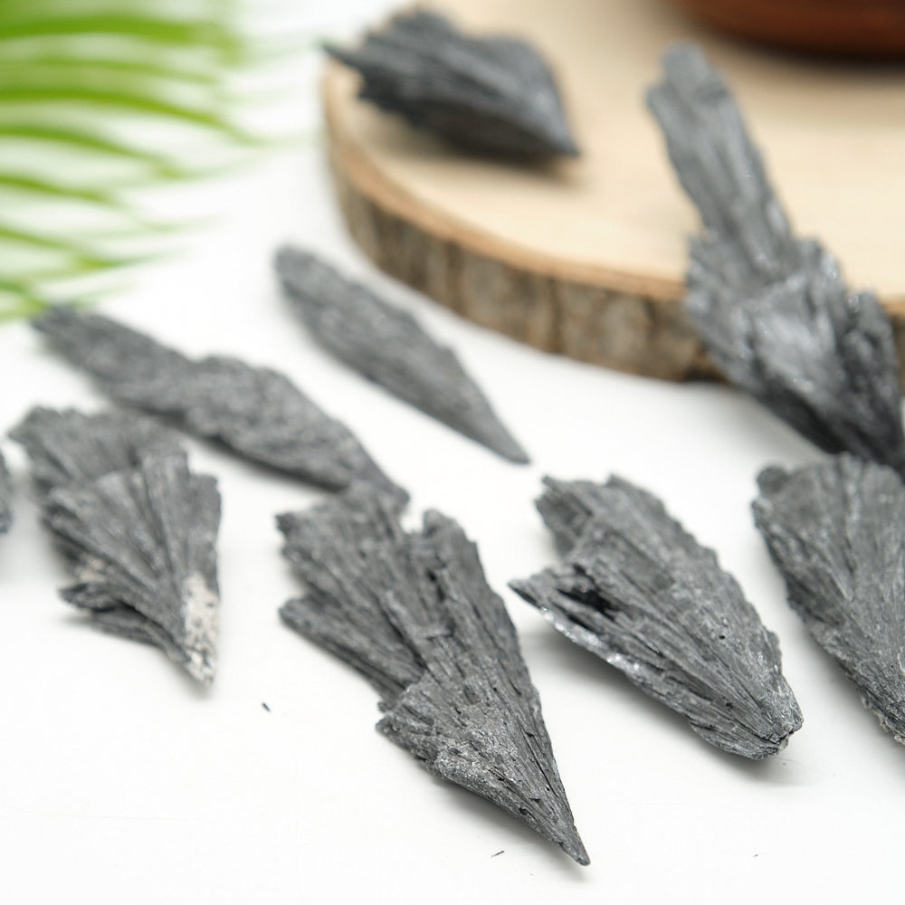 black kyanite fan crystals on a white surface with a wooden board in the background