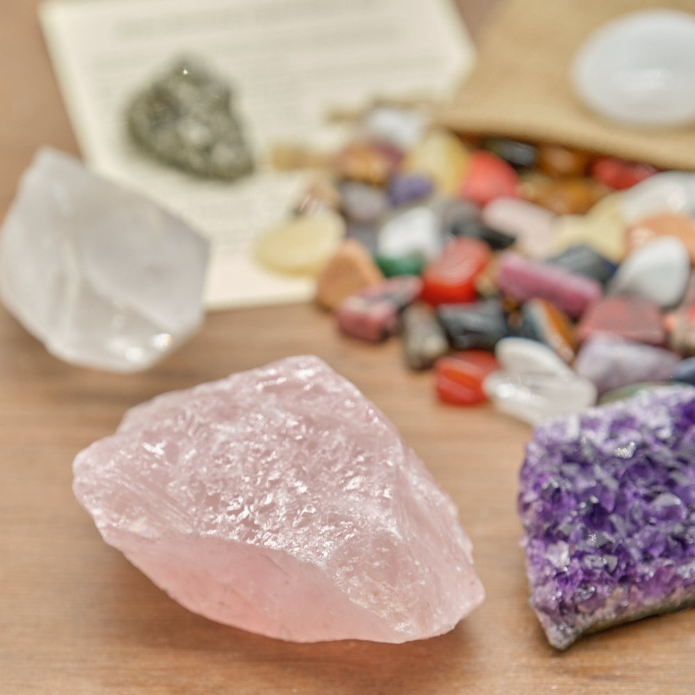 Close-up of a rose quartz on a wooden surface with other crystals in the background.