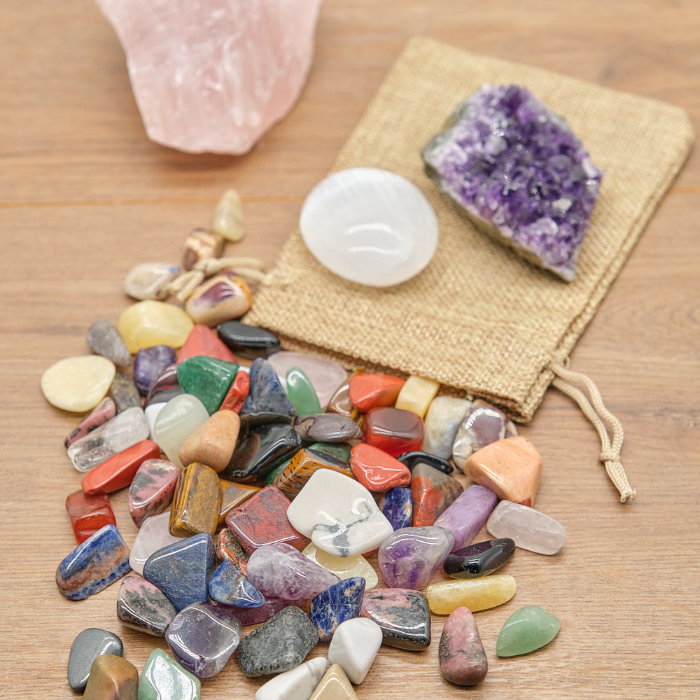 Assorted colorful crystals on a wooden surface with a white crystal and purple amethyst in the background.