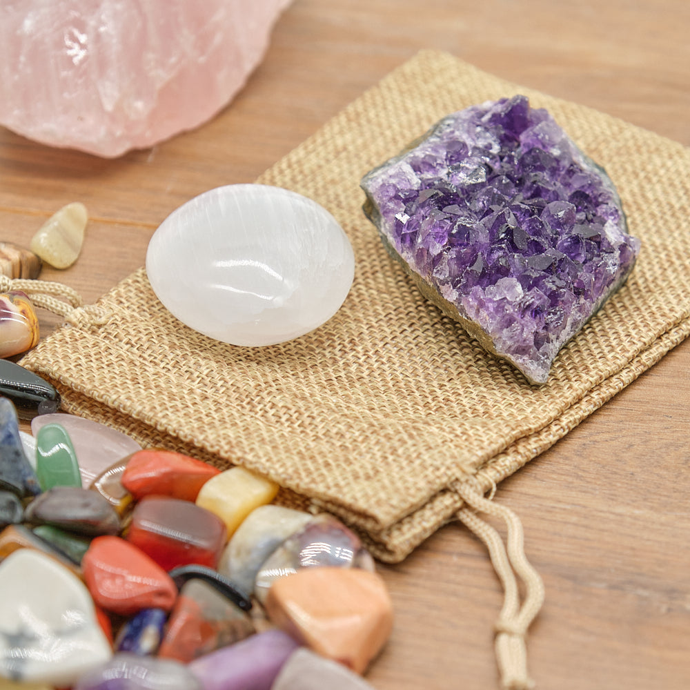 Collection of crystals including amethyst, rose quartz, and colorful tumbled stones on a wooden surface.