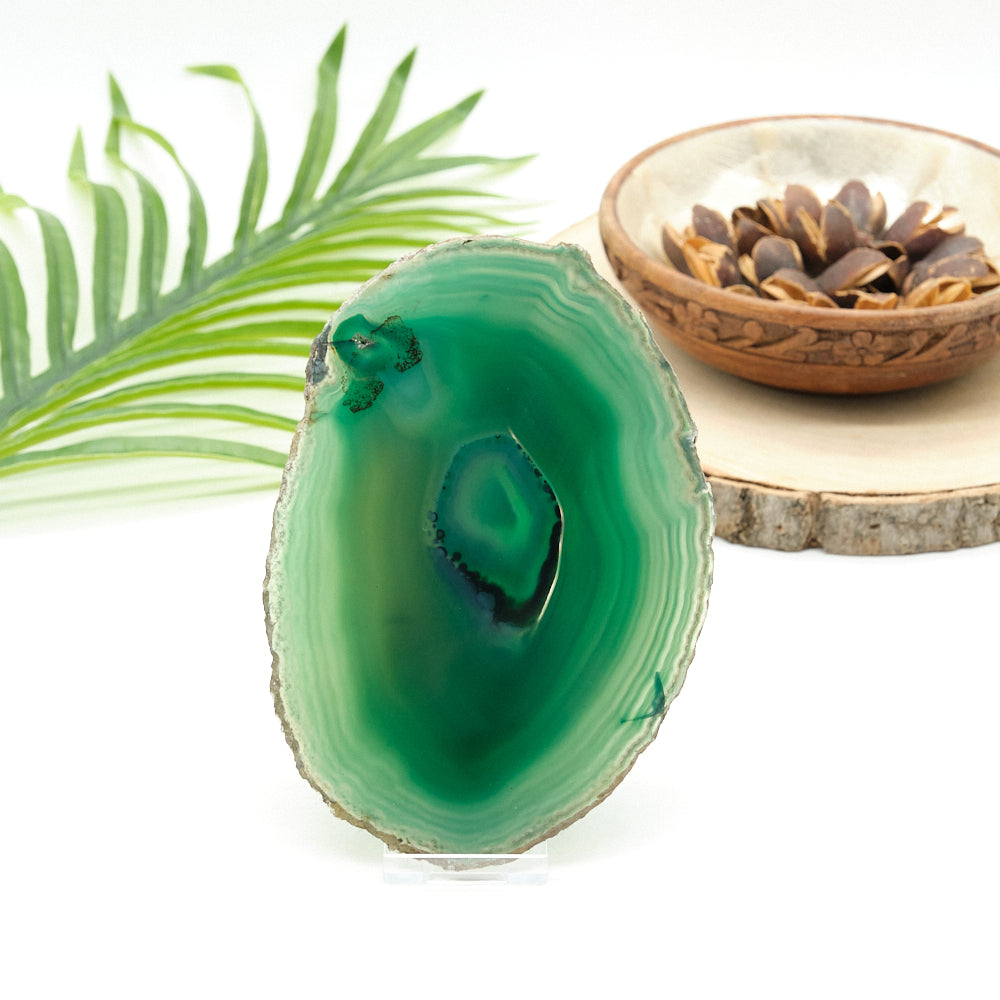 Green agate stone with a wooden bowl and leaves on a white background