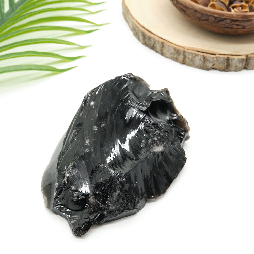 Black obsidian crystal rock on a white surface with a natural background