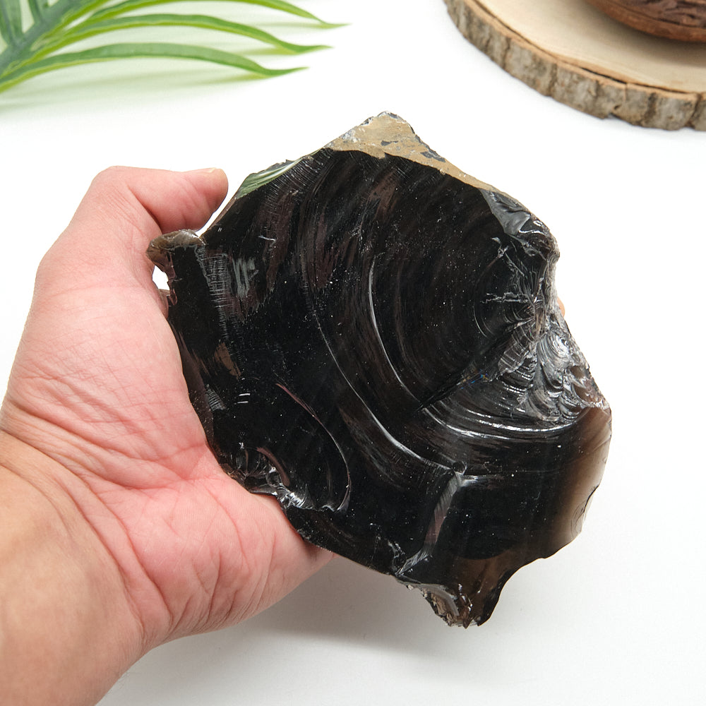 Hand holding a large black obsidian  stone with a white background
