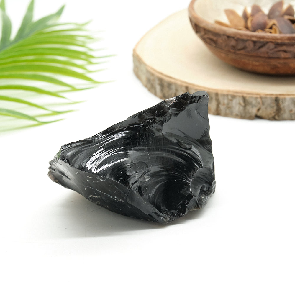 Black obsidian stone on a white surface with a blurred background
