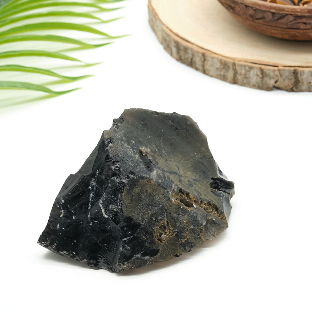 Black obsidian stone on a white surface with a natural background