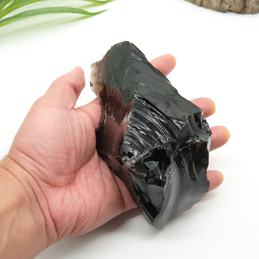 Hand holding a large black obsidian  crystal on a white background