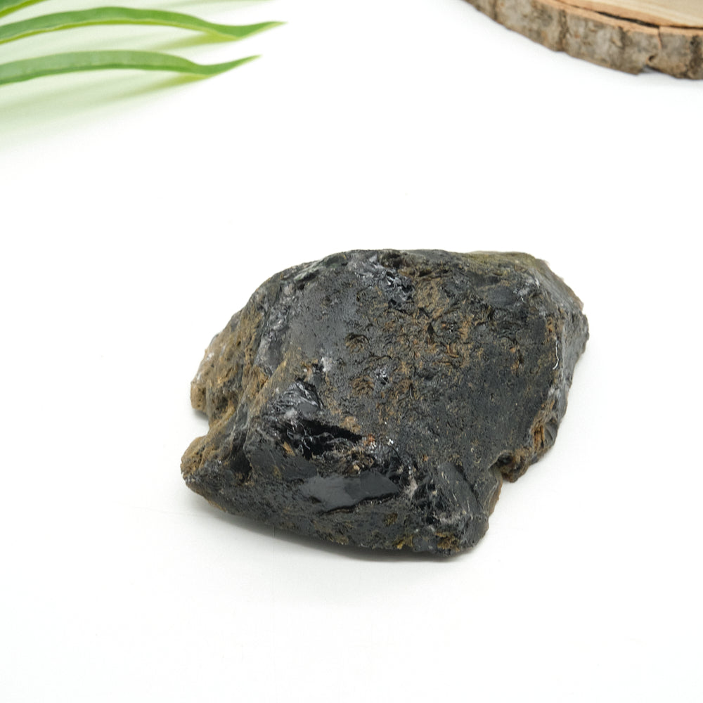 Black obsidian rock on a white background with green leaves