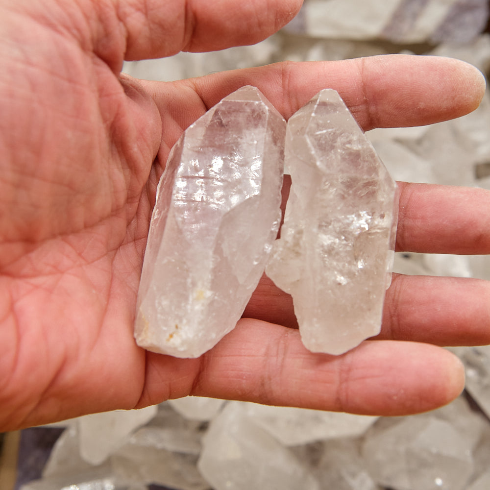 Two crystal points held in a hand with a blurred natural background