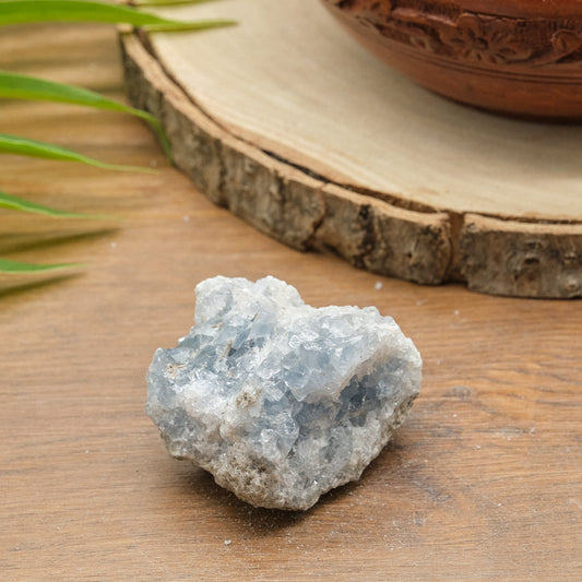 Raw celestite crystal on a wooden surface with a natural background