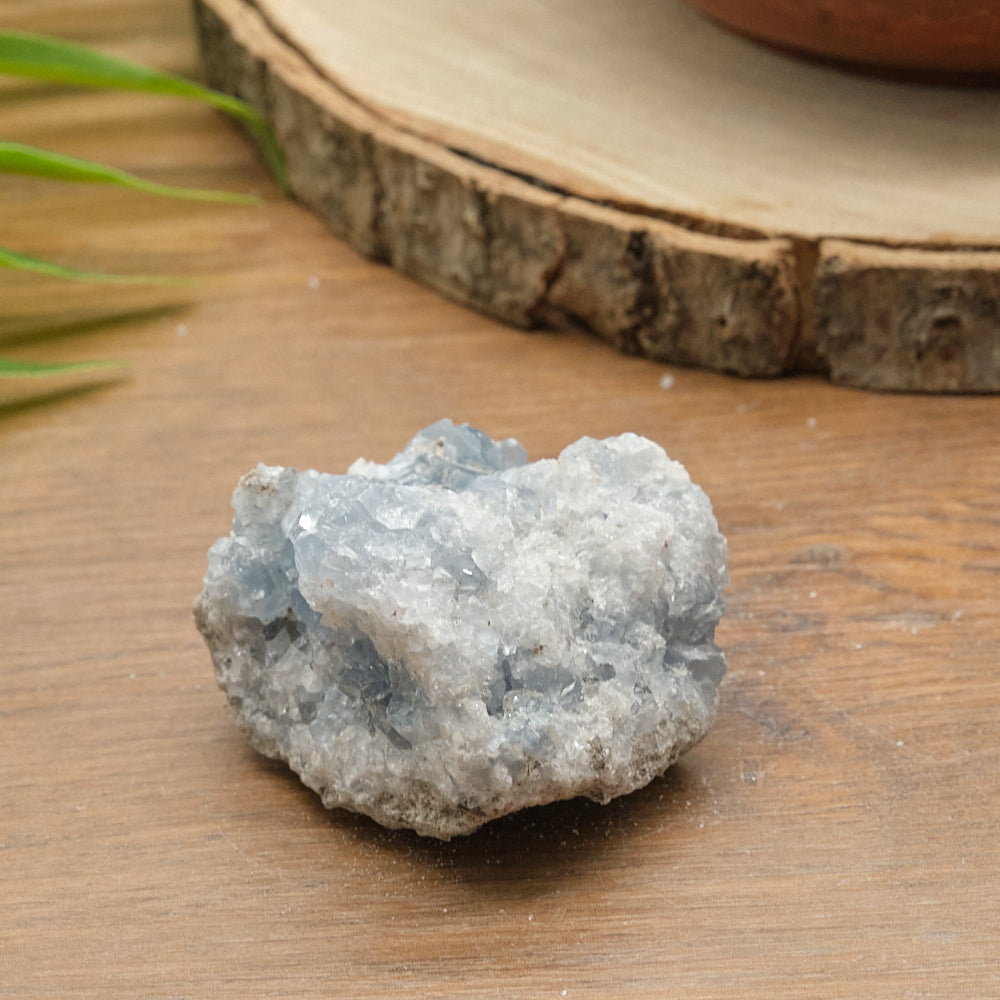 Raw celestite crystal rock on a wooden surface with a natural background