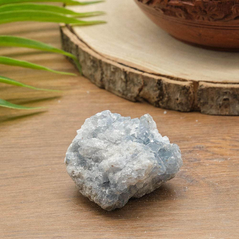 Raw celestite crystal on a wooden surface with a natural background
