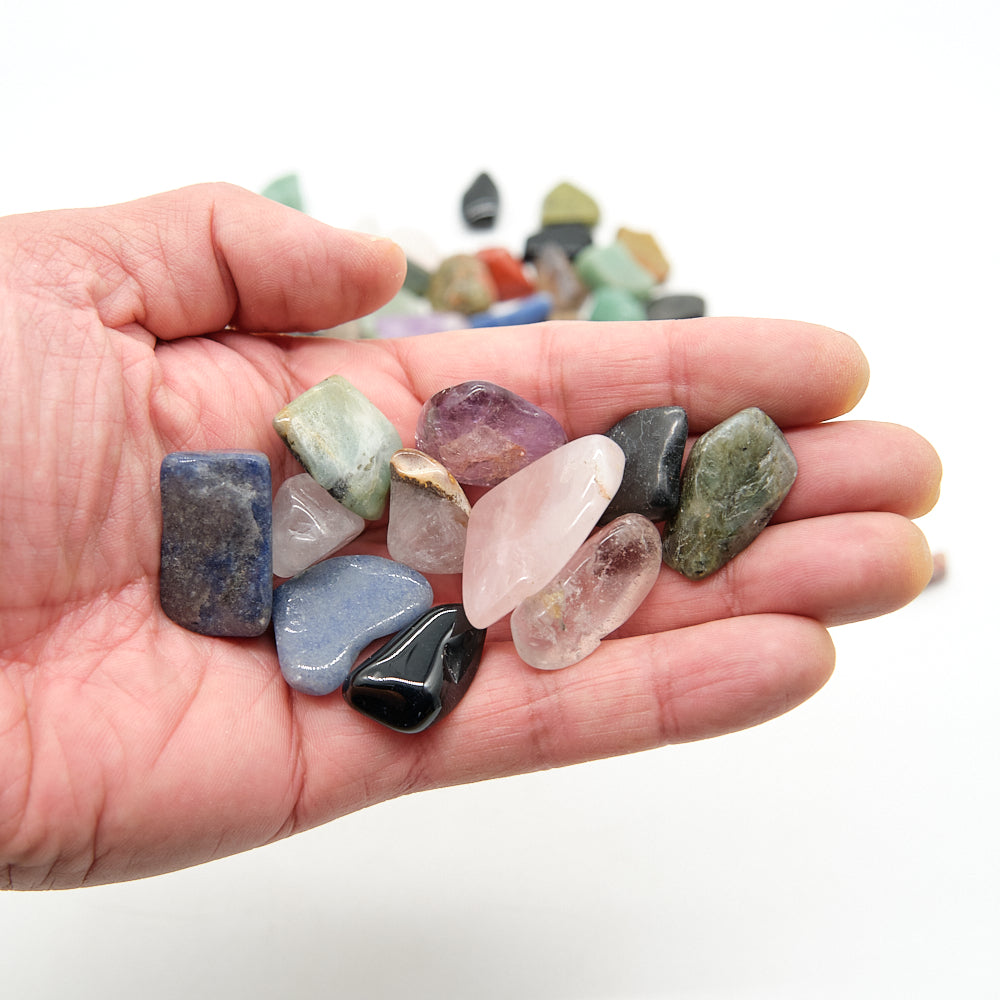 Hand holding a collection of multicolored gemstones with a blurred background