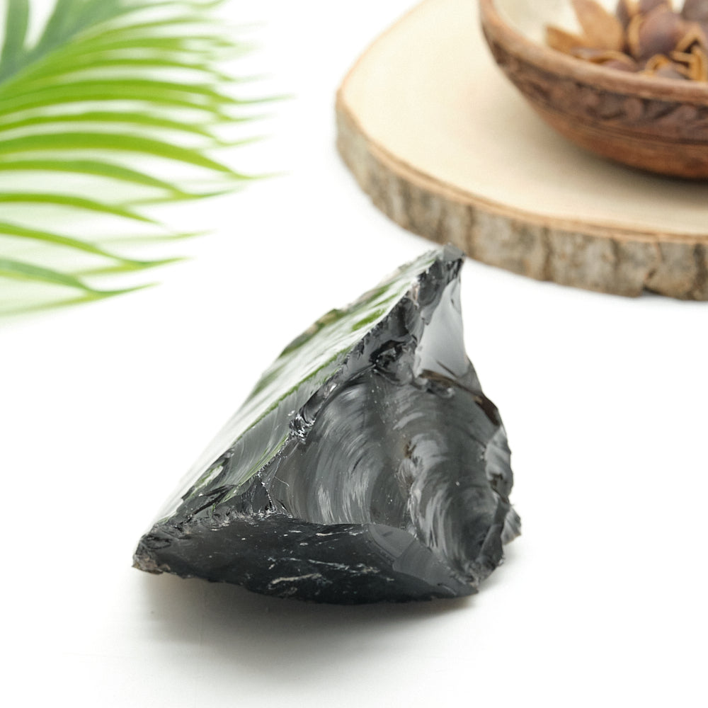 Raw obsidian stone with a leaf and wooden surface in the background