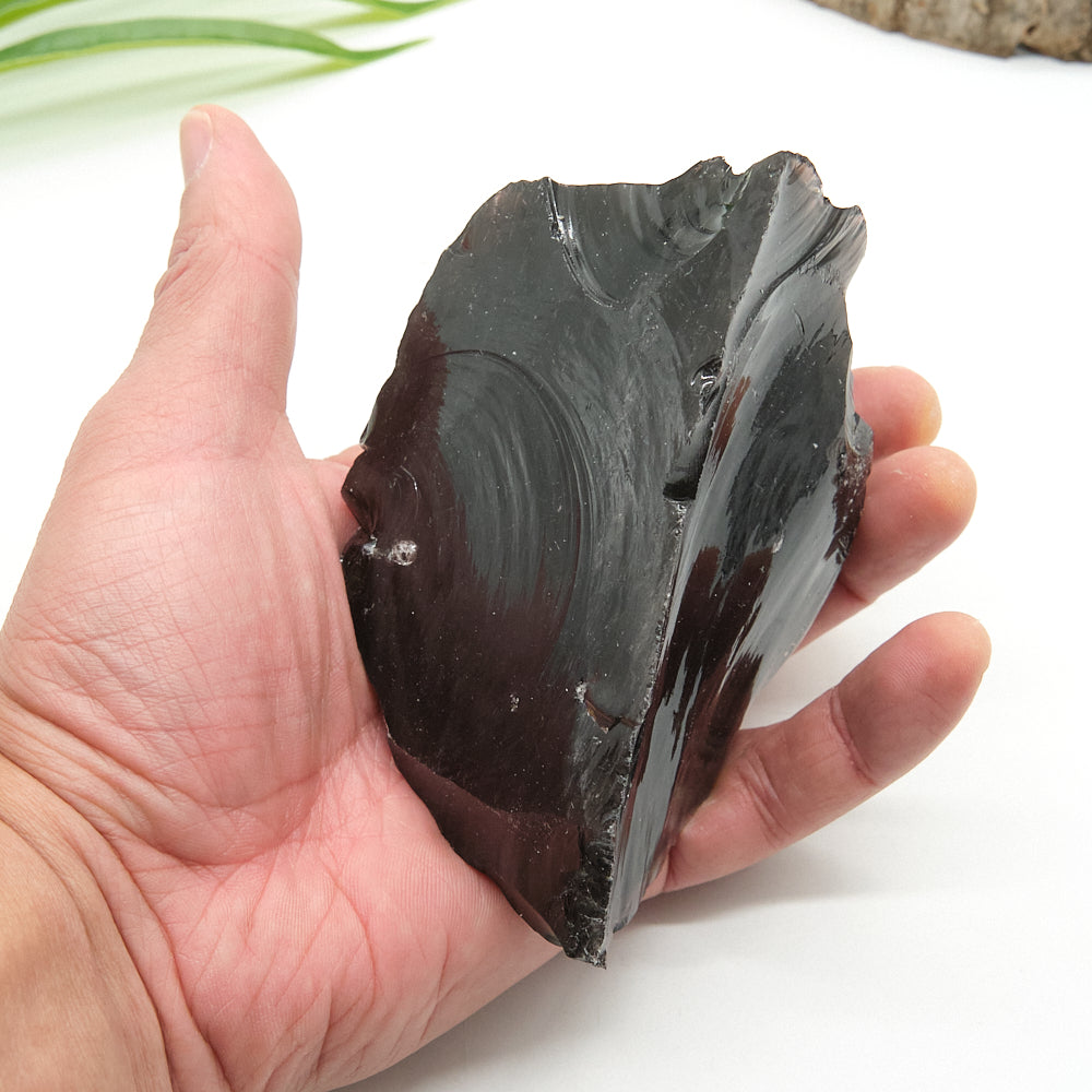 Hand holding a large obsidian stone against a white background