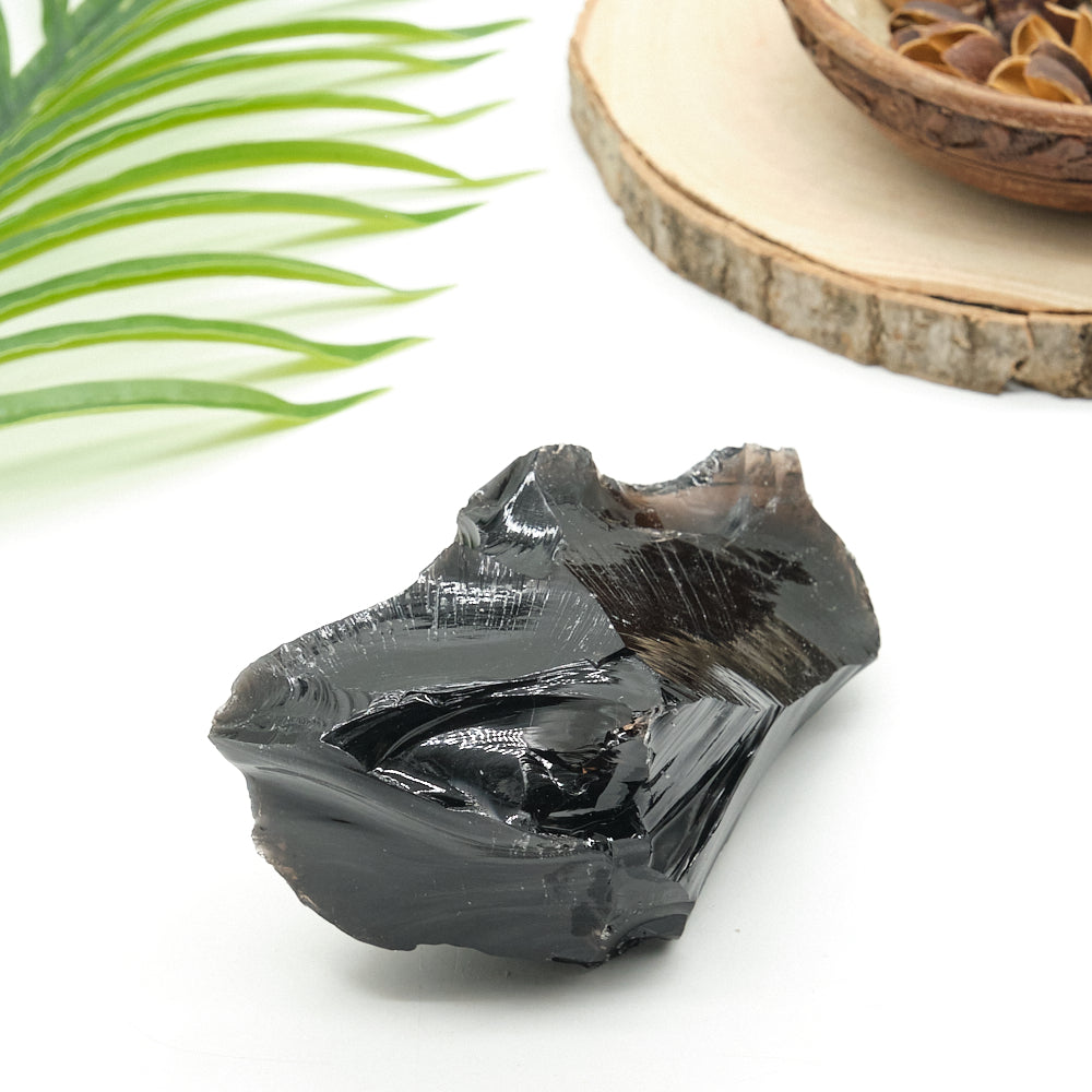 Black obsidian crystal on a white surface with a blurred background