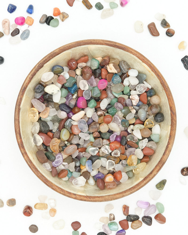 Small bowl filled with multicolored stones on a white background
