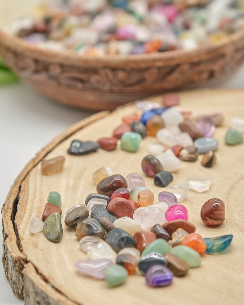Colorful crystal stones on a wooden surface with a blurred basket of stones in the background