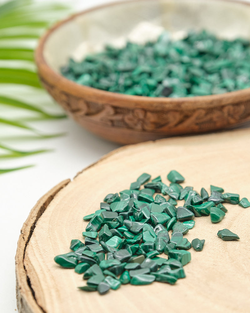 Green Malachite stones on a wooden surface with a bowl of stones in the background