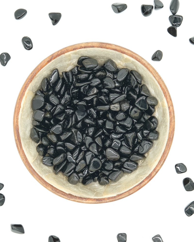Small bowl filled with Black Obsidian stones on a white background