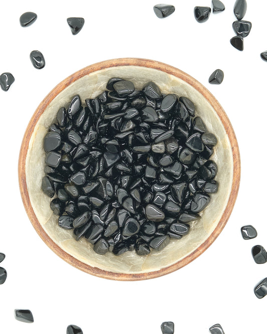 Small bowl filled with Black Obsidian stones on a white background